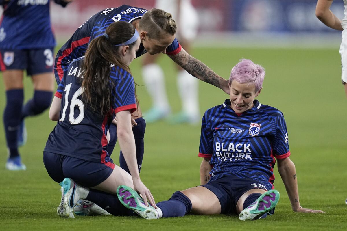 OL Reign forward Megan Rapinoe, right, talks to teammates Rose Lavelle (16) and Jess Fishlock.